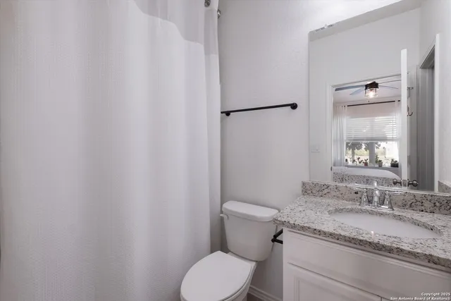 a bathroom with a granite countertop sink toilet and a mirror