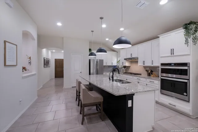 a kitchen with stainless steel appliances kitchen island granite countertop a sink and a refrigerator