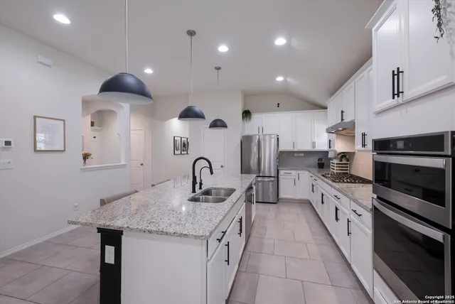 a kitchen with stainless steel appliances granite countertop a sink refrigerator and cabinets