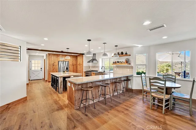 a kitchen with stainless steel appliances granite countertop a stove top oven a dining table and chairs with wooden floor