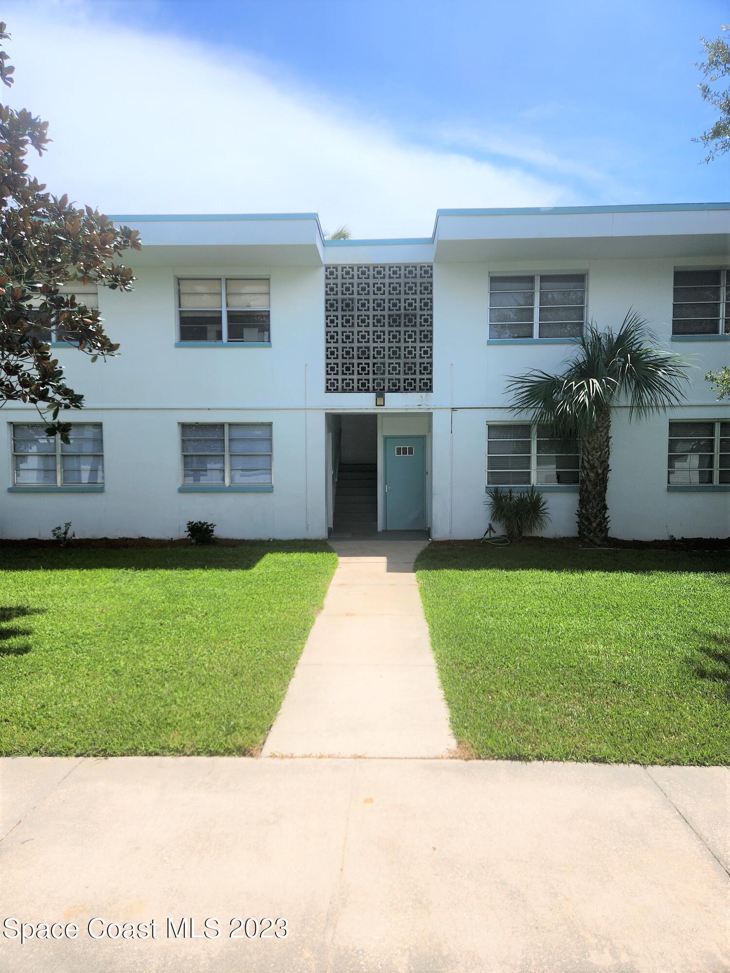 8401 North Atlantic Avenue, Unit K9 Cape Canaveral, FL 32920 - Photo 1 of 14 a front view of a house with a garden and yard