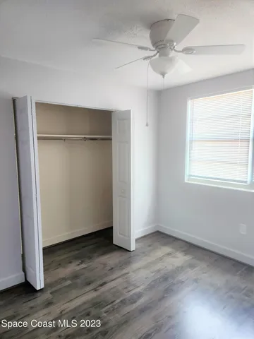 an empty room with wooden floor cabinet and windows