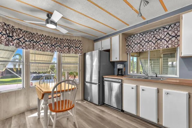 a kitchen with stainless steel appliances granite countertop a stove a refrigerator a dining table and chairs with wooden floor