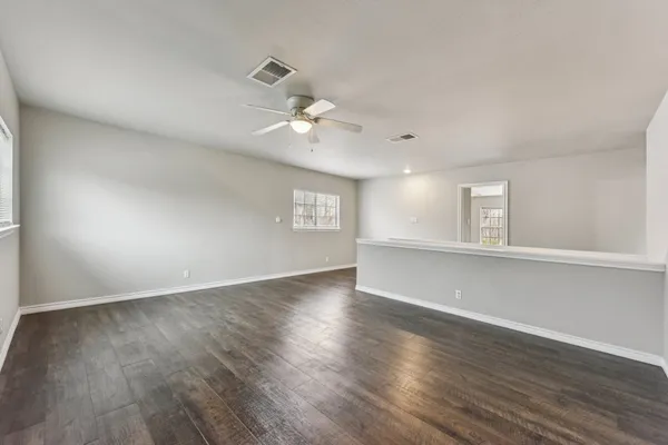 a view of an empty room with a window and wooden floor