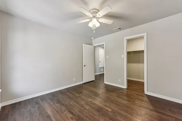 an empty room with wooden floor and a ceiling fan