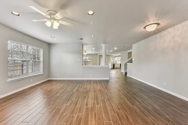 a view of an empty room with a window and wooden floor