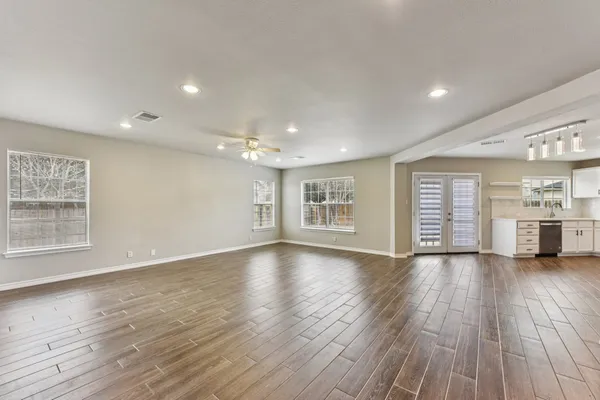 a view of a big room with wooden floor and windows