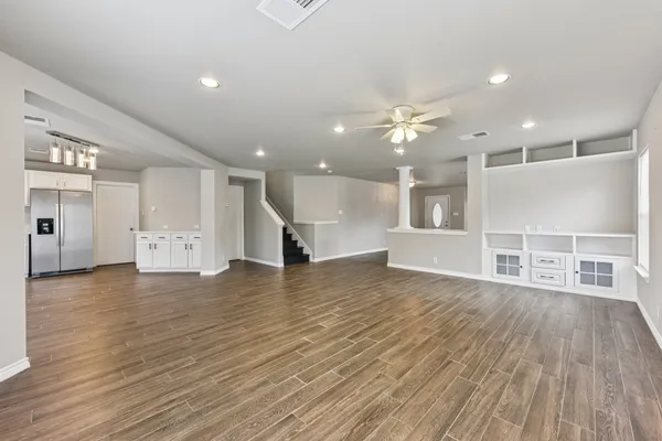a view of a room with wooden floors and kitchen view