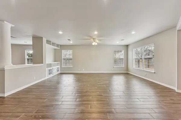a view of an empty room with wooden floor and a window