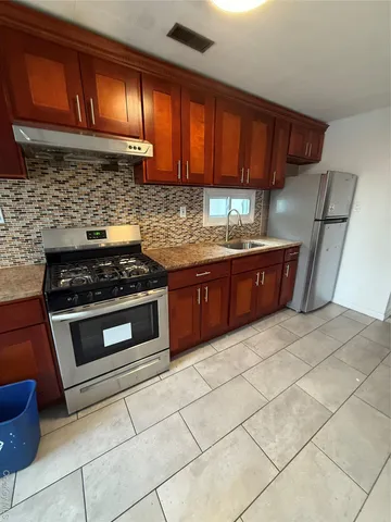 a kitchen with granite countertop a stove and a wooden cabinets