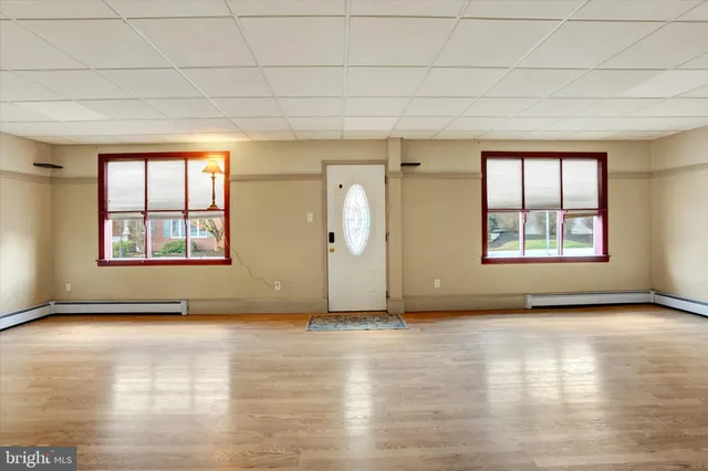 an empty room with wooden floor and windows