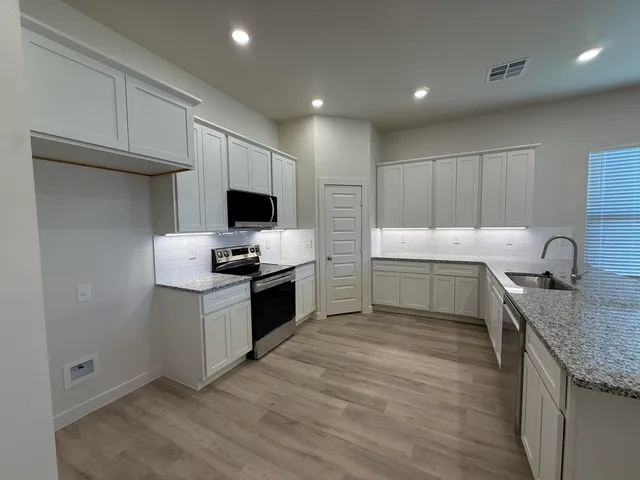 a kitchen with granite countertop a sink and a stove top oven with wooden floor