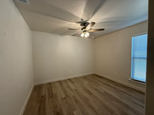 an empty room with a window and ceiling fan