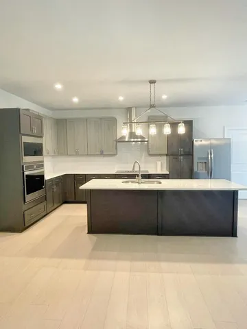 a large kitchen with granite countertop a large counter top stainless steel appliances and cabinets