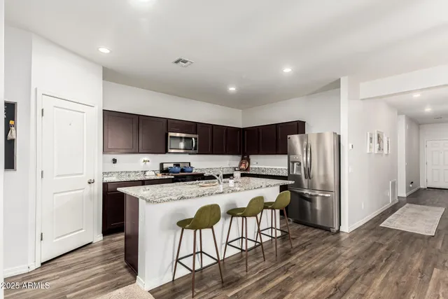 a kitchen with stainless steel appliances a refrigerator a stove a sink and white cabinets with wooden floor