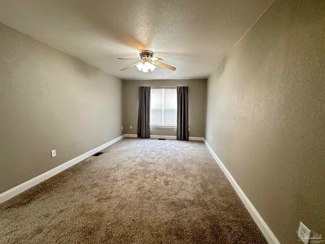 an empty room with windows and ceiling fan
