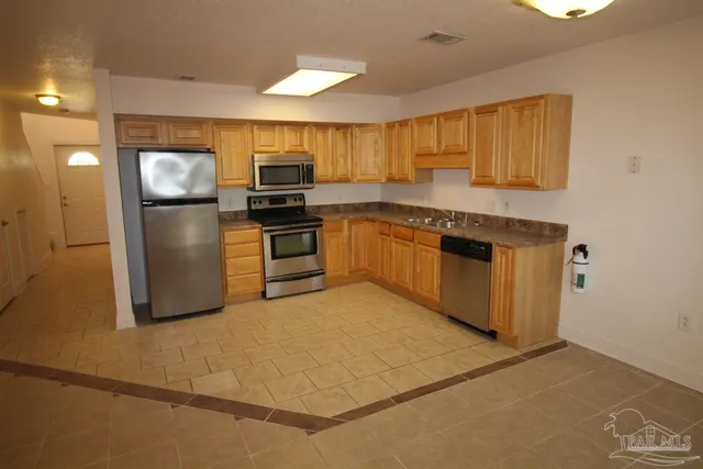 a kitchen with stainless steel appliances granite countertop a refrigerator a stove and a sink