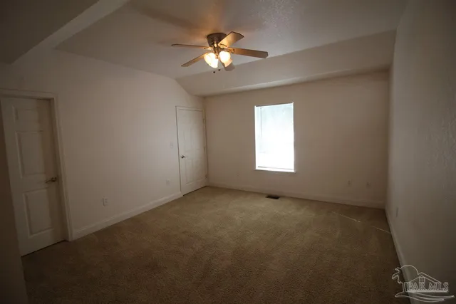 an empty room with windows and chandelier fan