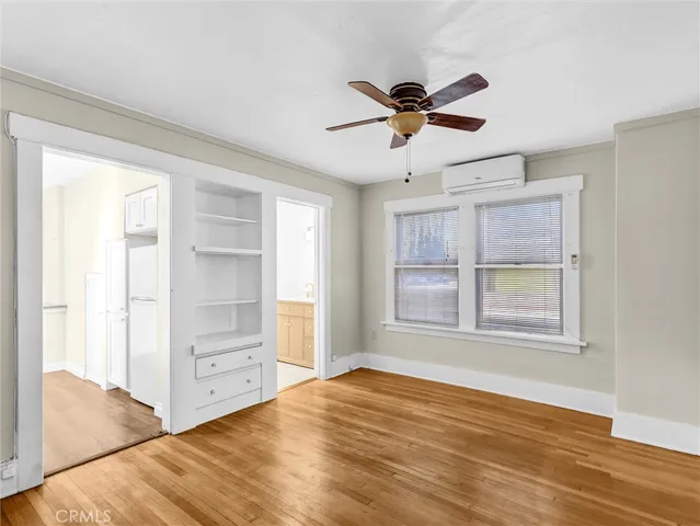 a view of empty room with wooden floor and fan
