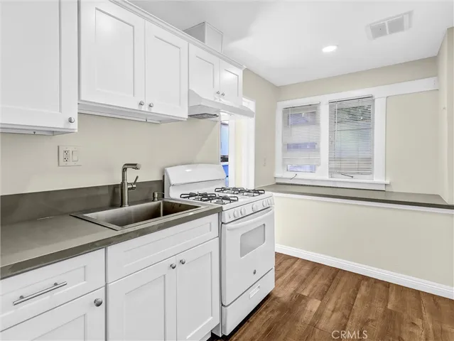 a kitchen with granite countertop white cabinets and a stove