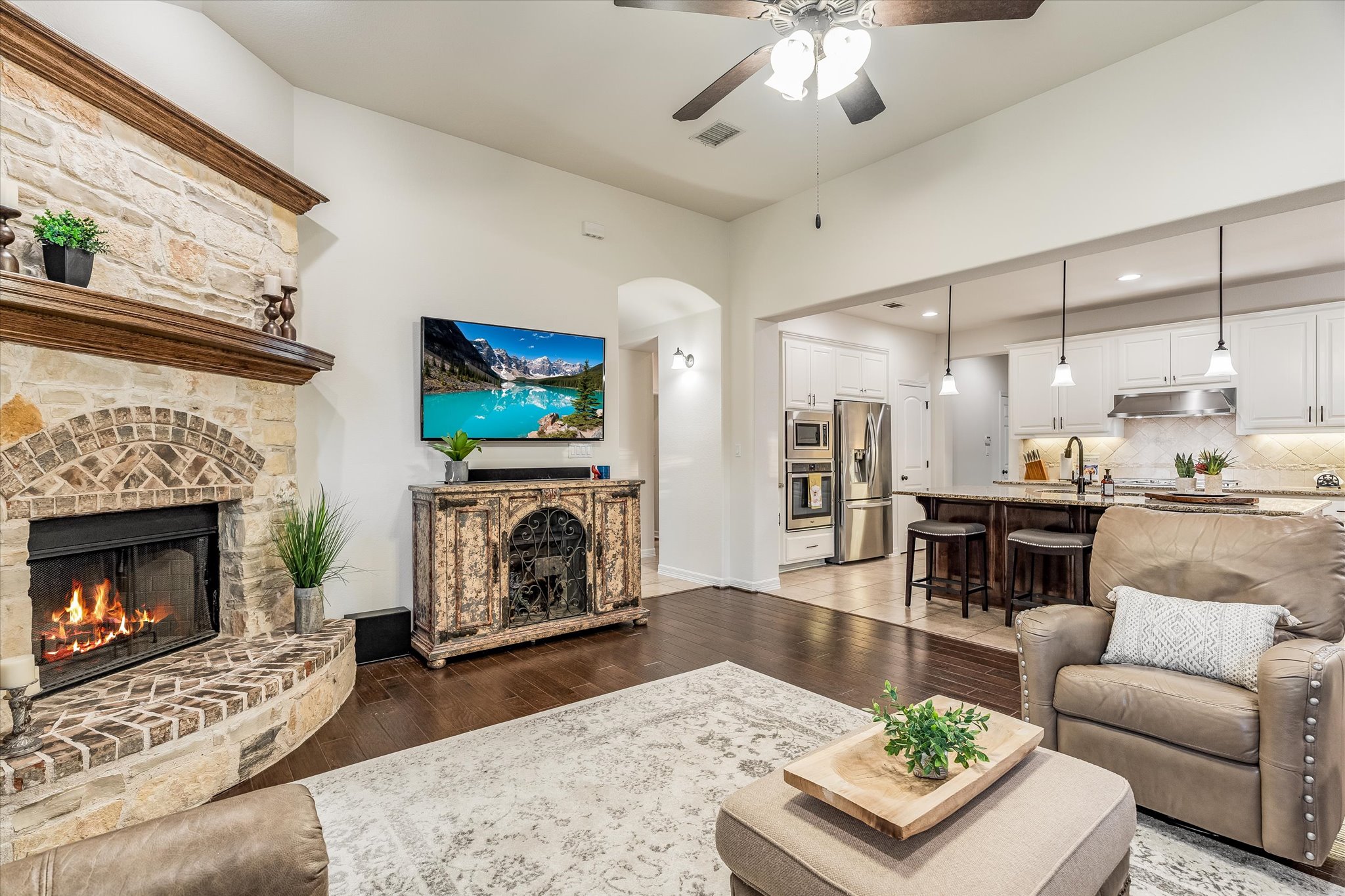 226 Galloway Lane Austin, TX 78737 - Photo 9 of 30 Living room featuring a fireplace, a ceiling fan, dark wood-style flooring, arched walkways, and recessed lighting