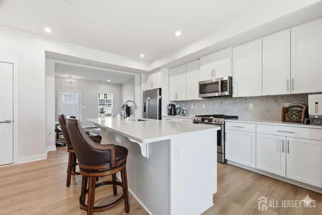 a kitchen with stainless steel appliances granite countertop a white cabinets a sink and a stove