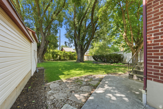 270 East 700 North Logan, UT 84321 - Photo 32 of 42 Expansive backyard featuring mature trees, a manicured lawn, and a concrete patio with stone pavers
