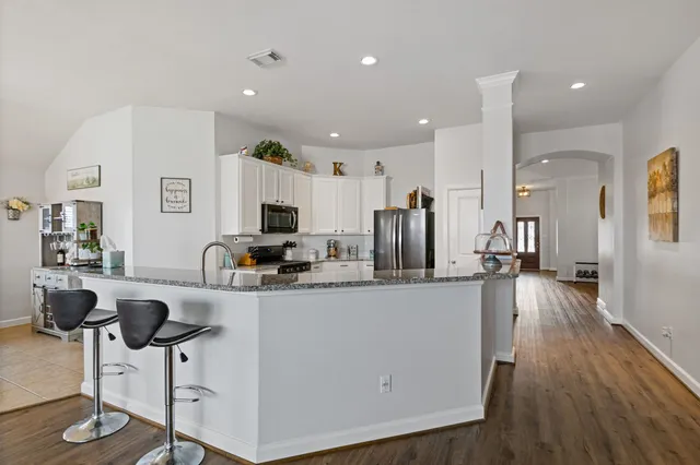 a living room with furniture a wooden floor and a kitchen view