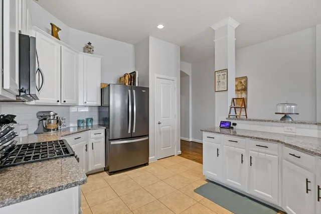 a kitchen with stainless steel appliances kitchen island granite countertop a refrigerator a stove a sink a dining table and chairs with wooden floor
