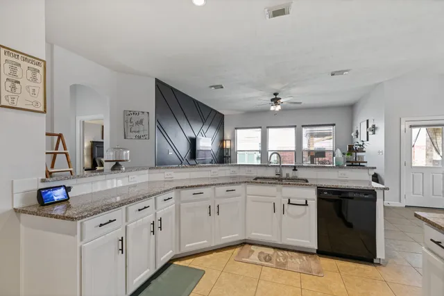 a kitchen with stainless steel appliances granite countertop a refrigerator oven a sink dishwasher and white cabinets with wooden floor