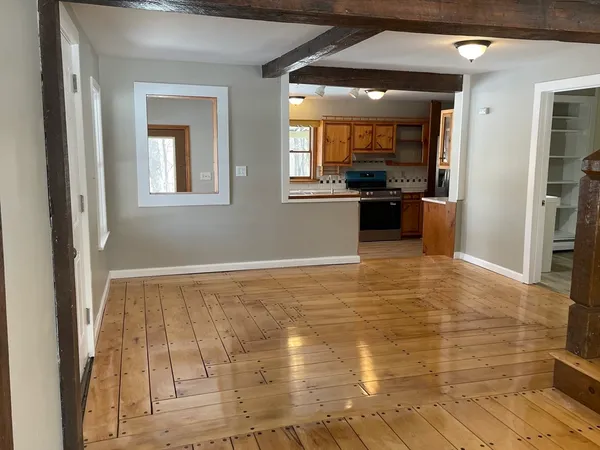 a view of a hallway with wooden floor and a kitchen