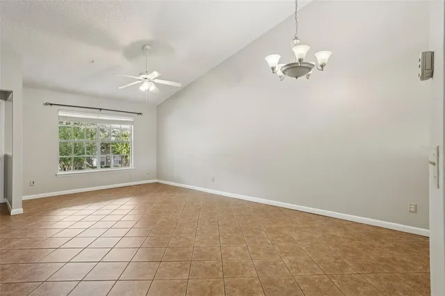 an empty room with a chandelier fan and windows