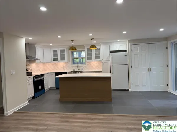 a large kitchen with stainless steel appliances kitchen island granite countertop a stove a sink and a refrigerator
