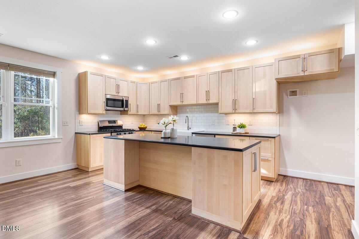 1616 Bowling Road Fuquay-Varina, NC 27526 - Photo 22 of 33 a kitchen with kitchen island granite countertop a sink cabinets and wooden floor