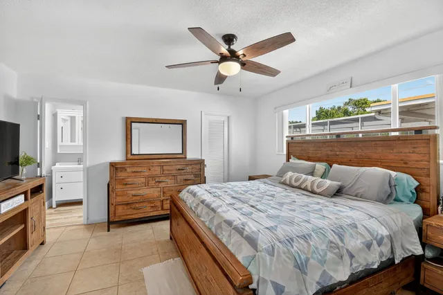 a bedroom with a large bed a flat tv screen and a chandelier