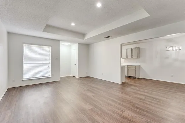 an empty room with wooden floor cabinet and windows