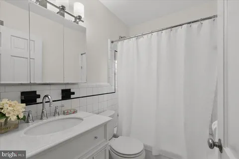 a bathroom with a granite countertop sink vanity mirror and toilet