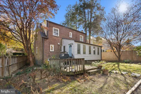 a front view of a house with a yard covered with snow and trees