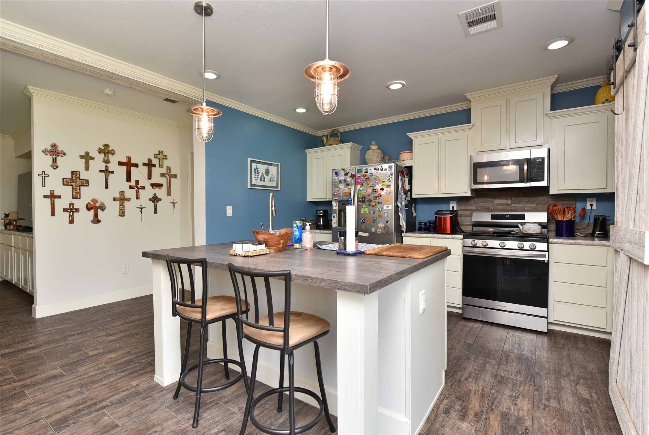 3221 Pecha Lane Rosenberg, TX 77471 - Photo 9 of 46 a kitchen with stainless steel appliances a kitchen island hardwood floor sink stove dining table and chairs