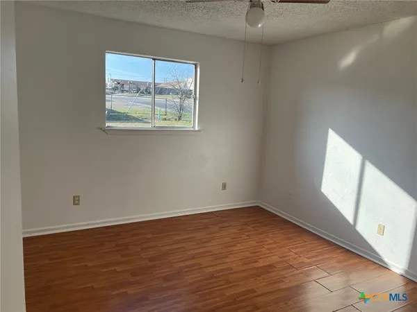 an empty room with wooden floor and windows