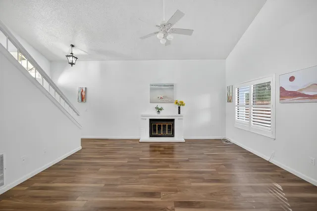 a view of a livingroom with wooden floor a ceiling fan and windows