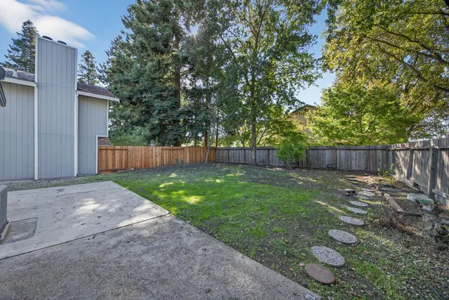 a view of a backyard with a trees and wooden fence
