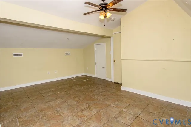 an empty room with a ceiling fan and carpet