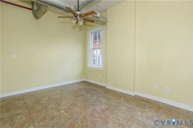 an empty room with windows and fan