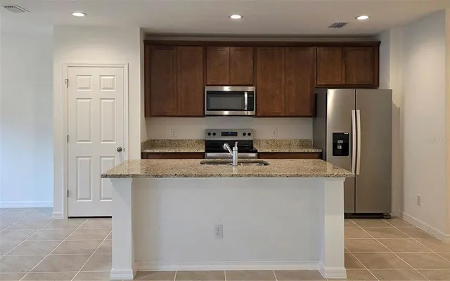 a kitchen with stainless steel appliances granite countertop a stove a sink and a refrigerator with wooden floor