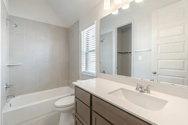 a bathroom with a bathtub shower sink vanity mirror and toilet