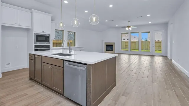 a open kitchen with kitchen island a sink dishwasher stove and oven with wooden floor