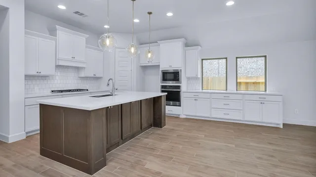 a kitchen with stainless steel appliances granite countertop a stove a sink and a refrigerator