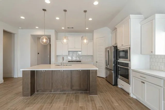 a large kitchen with a center island wooden floor stainless steel appliances and windows