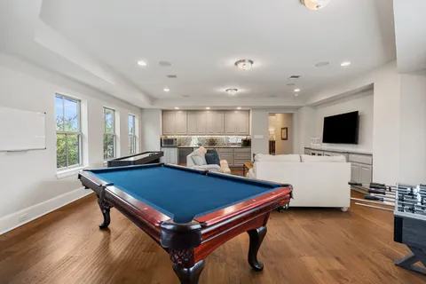 a living room with pool table flat screen tv and windows